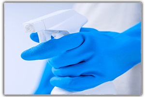 Spray bottle with disinfectant being held by blue glove